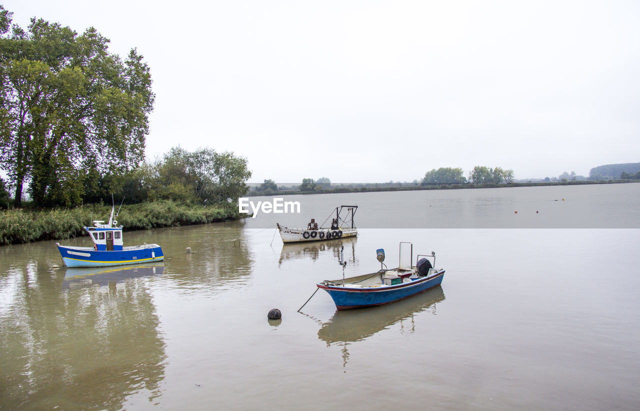 Boats moored on river against clear sky