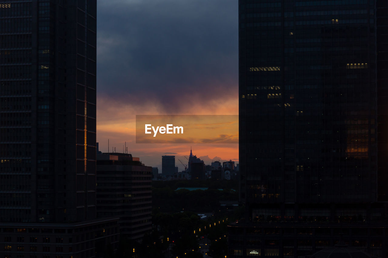 Modern buildings in city against sky during sunset