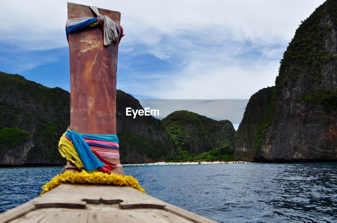 Cropped image of boat in river against mountains and sky