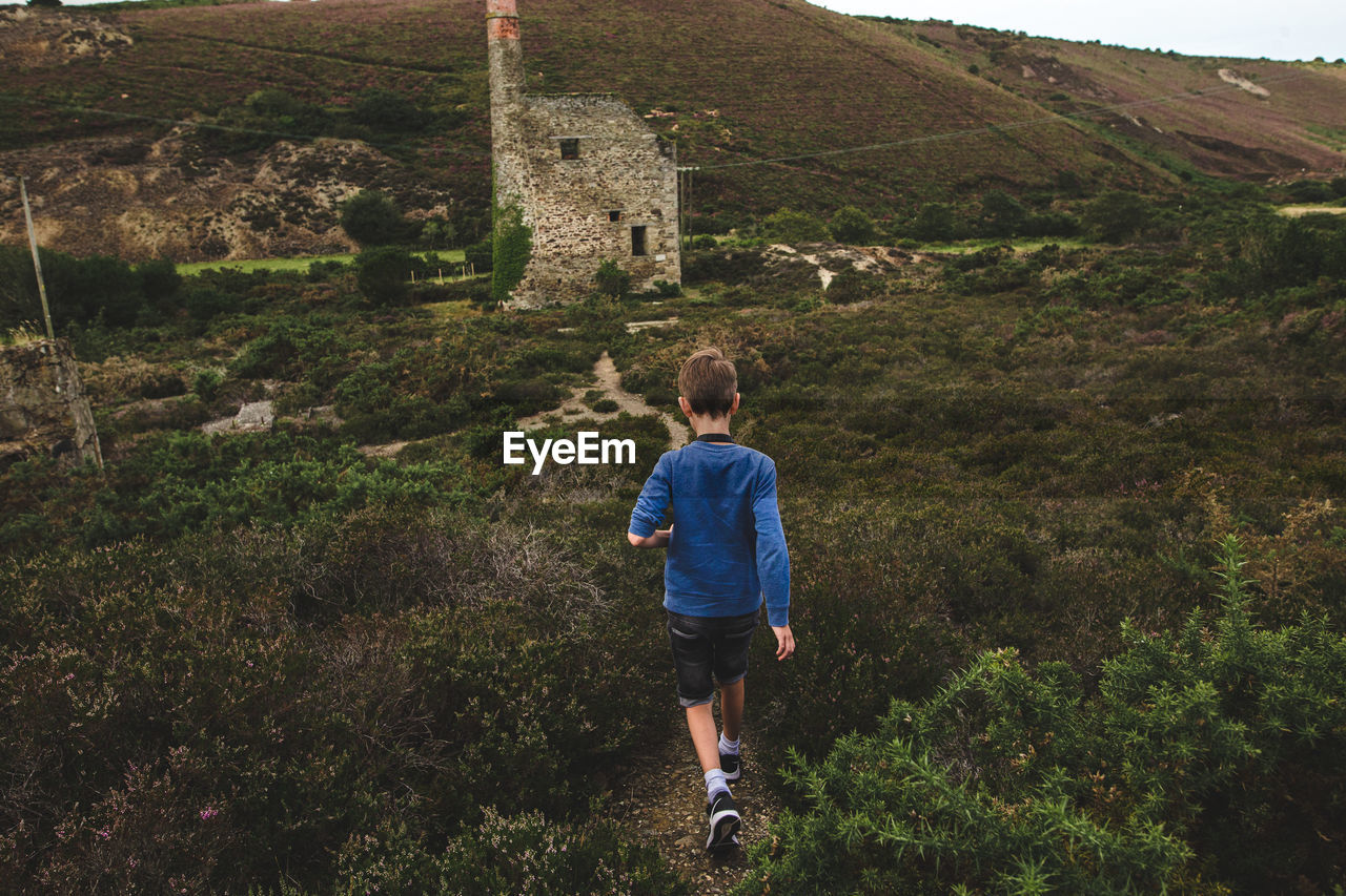 REAR VIEW OF BOY LOOKING AT MOUNTAIN