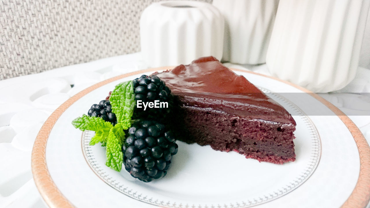 Close-up of brownie with blackberries served on table