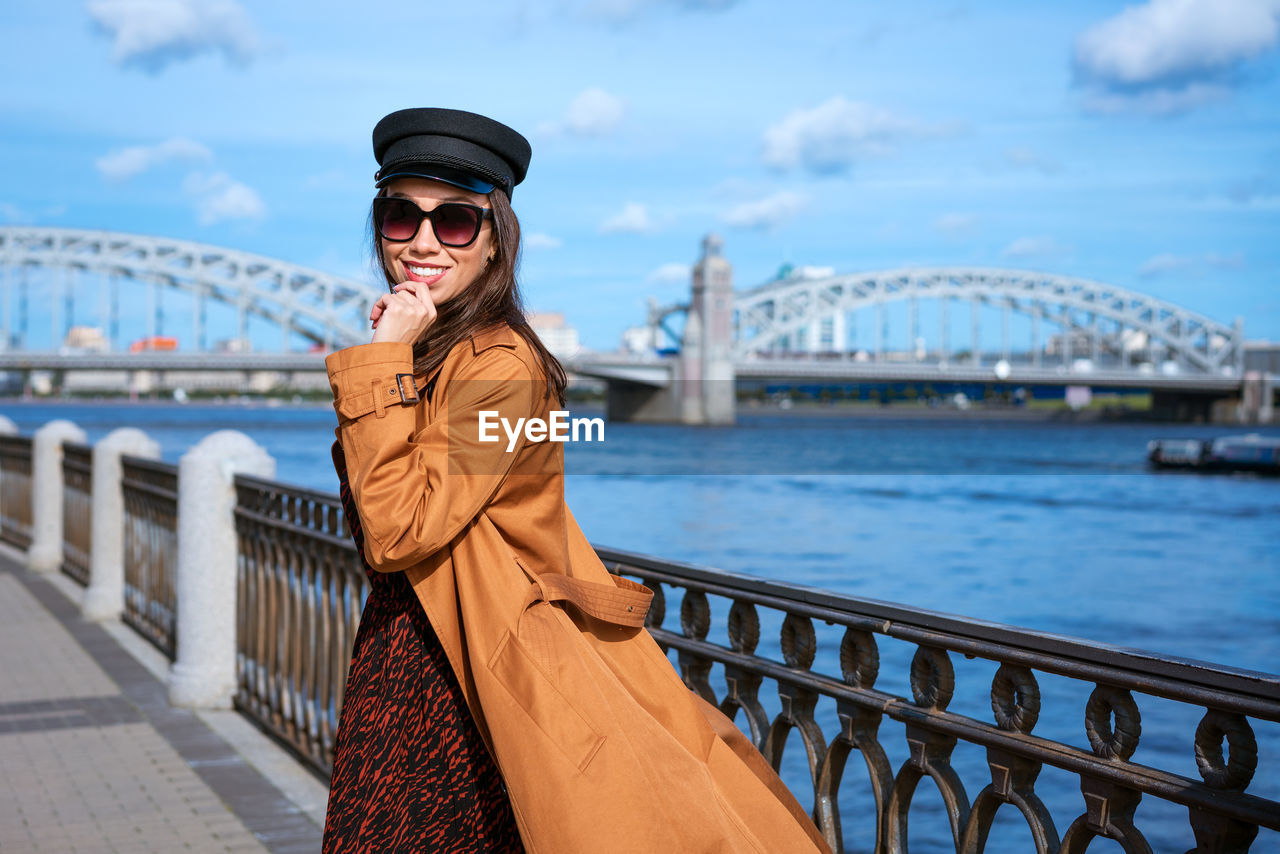 Beautiful young woman in a raincoat on the embankment