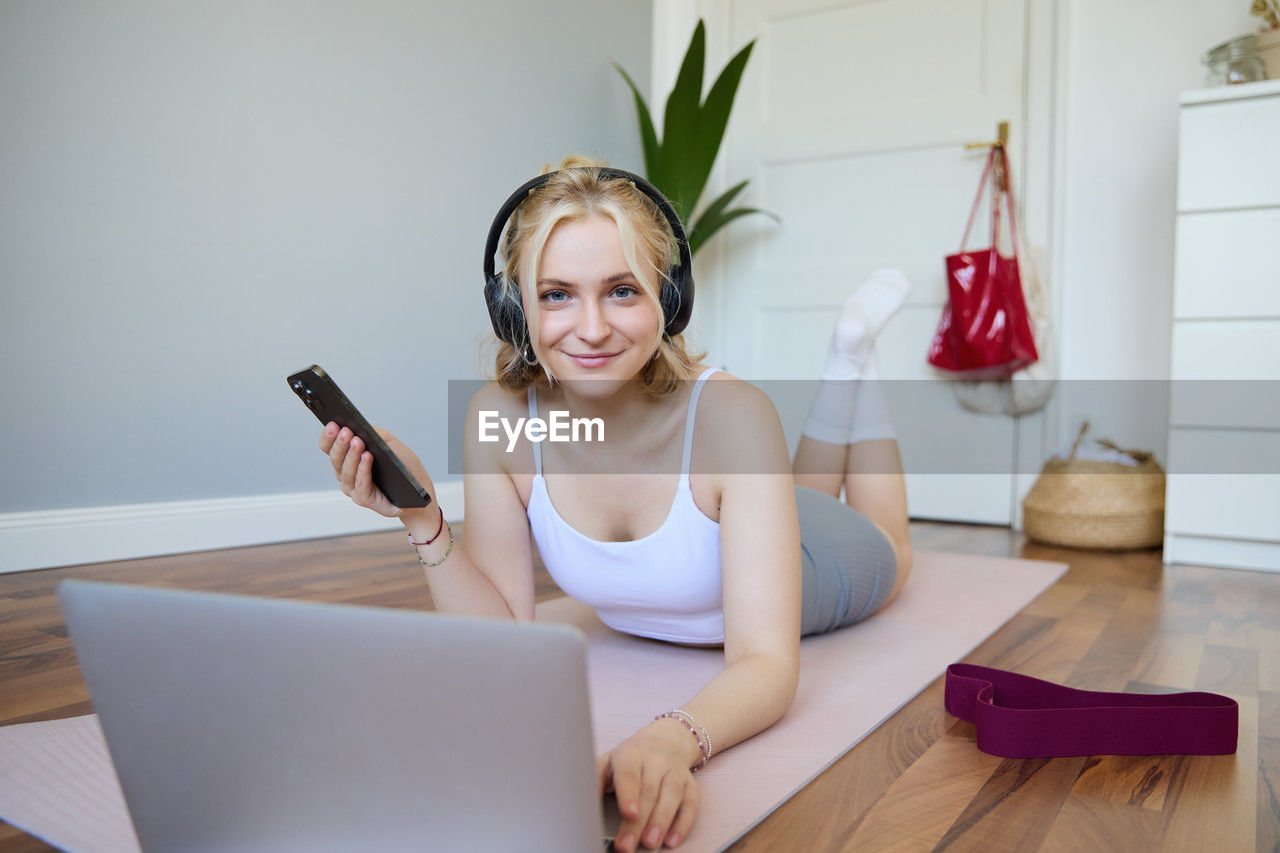 portrait of young woman using mobile phone while sitting on table at home