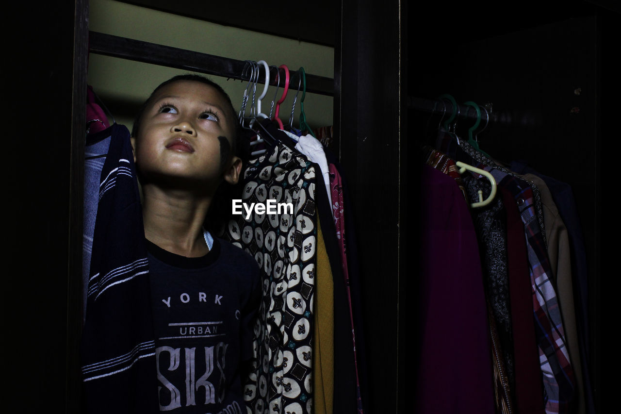 Boy looking up while standing in wardrobe