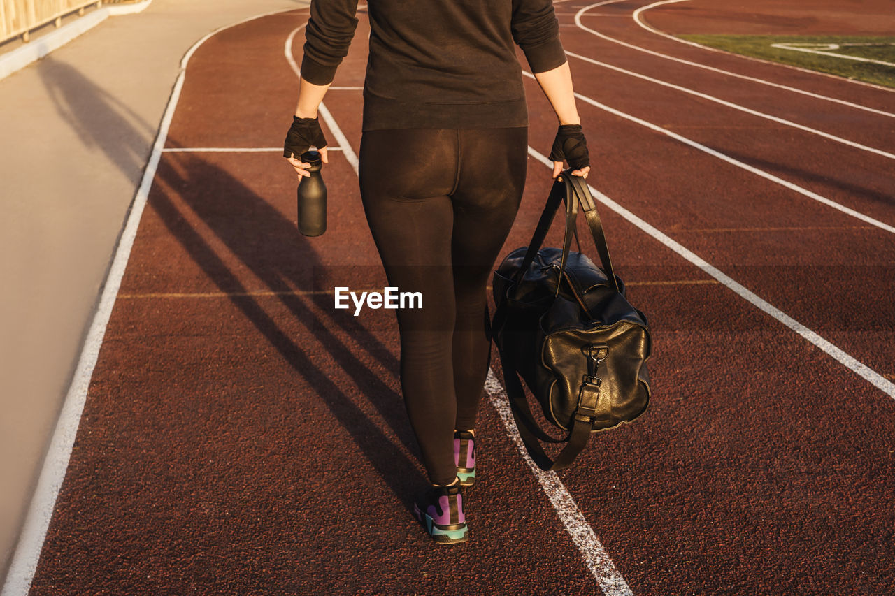 Low section of woman walking on running track