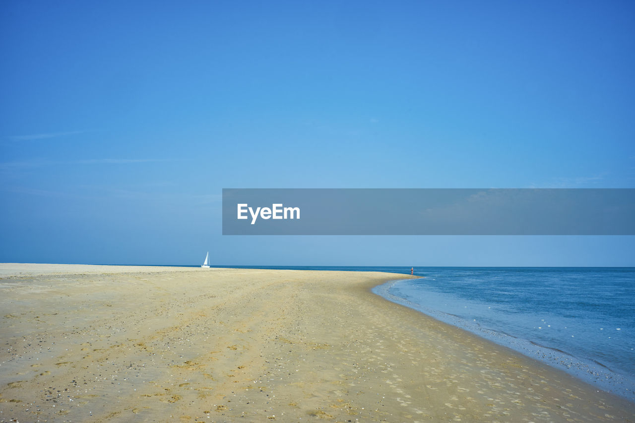 Scenic view of beach against clear blue sky