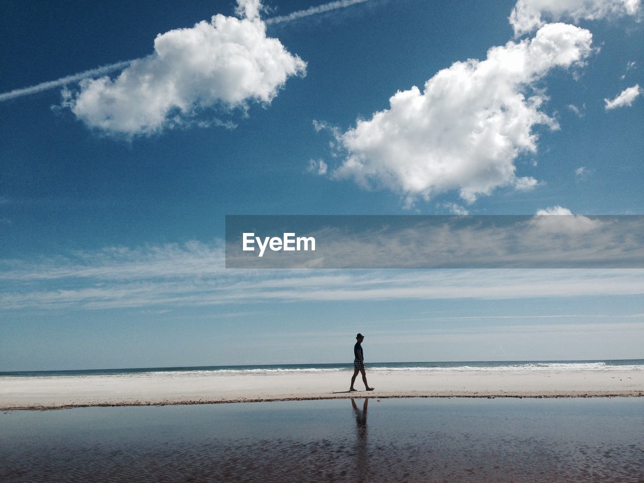 REAR VIEW OF MAN WALKING AT BEACH