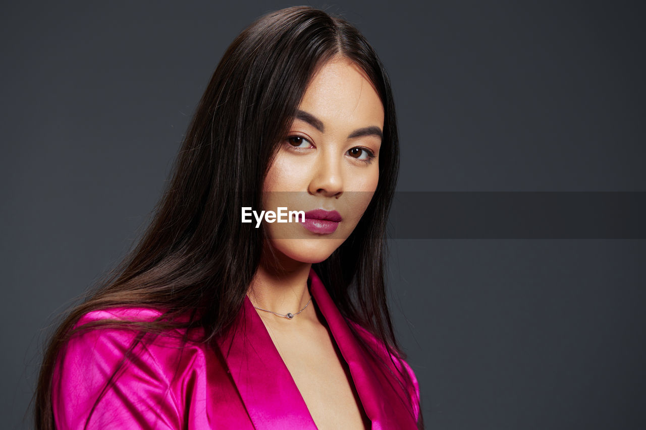 portrait of beautiful young woman against black background