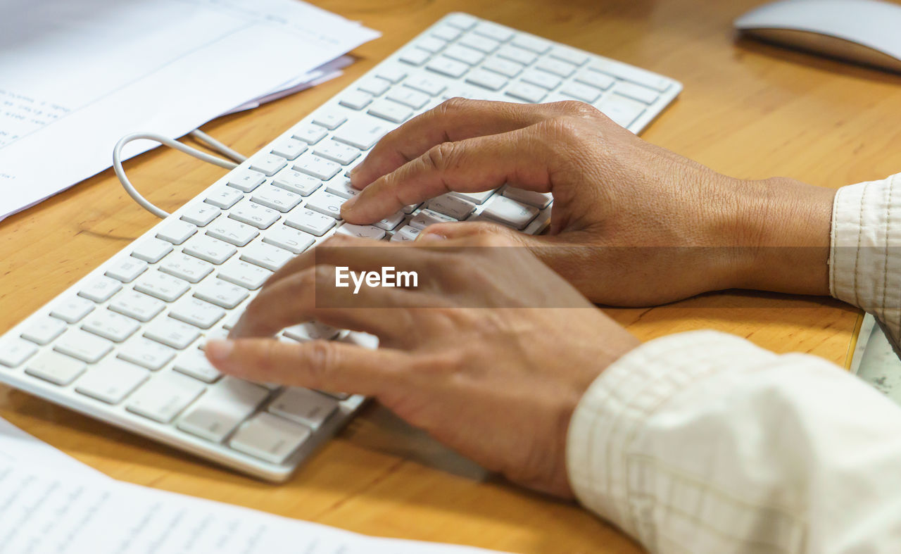 Cropped hands of businessman typing on keyboard in office