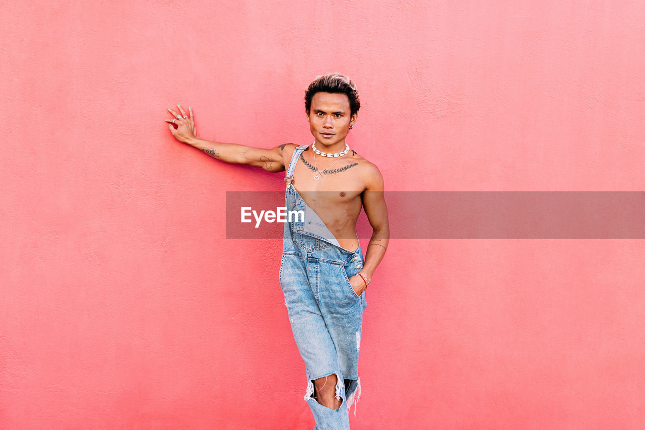 Portrait of young woman standing against yellow background