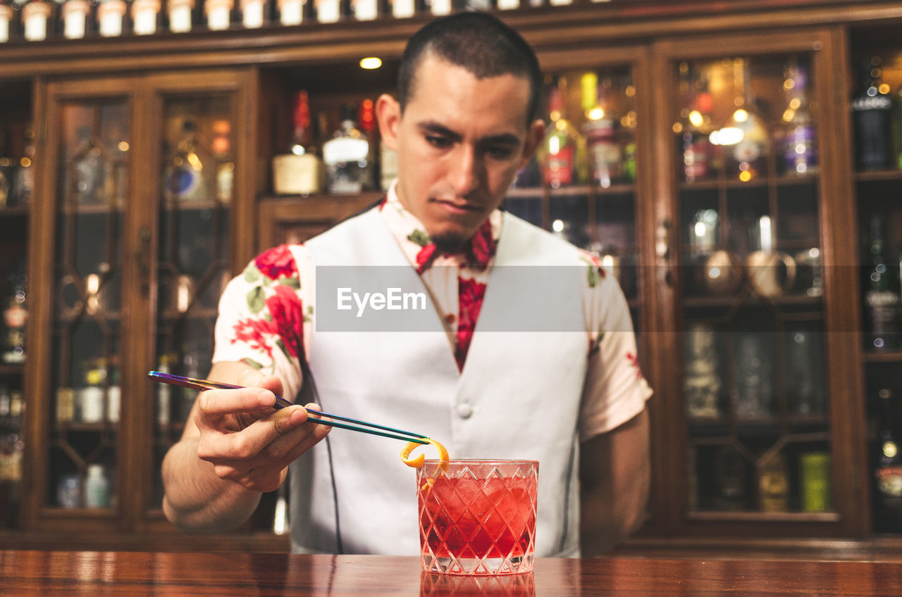 MID ADULT MAN HOLDING GLASS WHILE STANDING AT BEACH