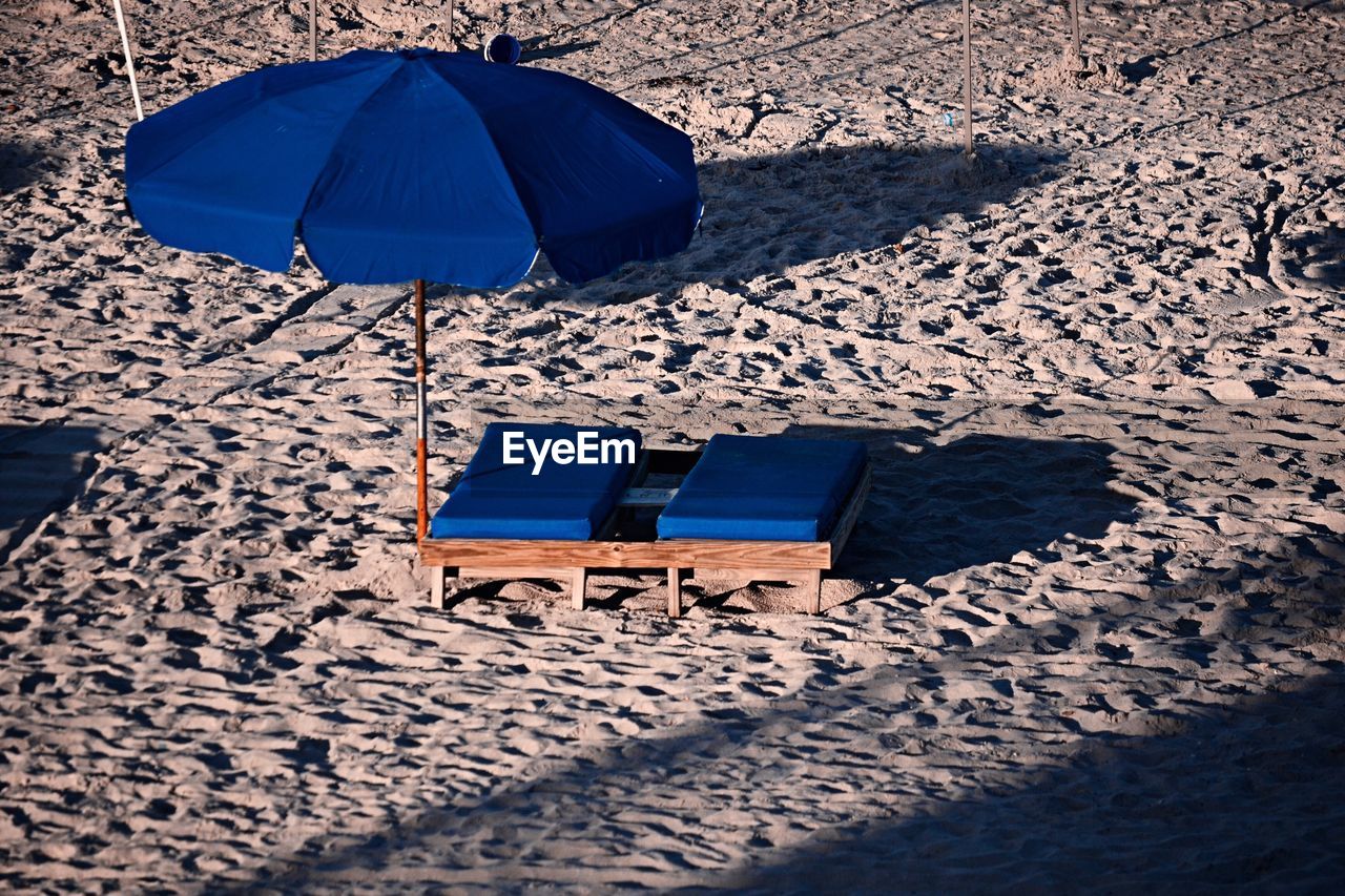 High angle view of blue lounge chairs and parasol at beach