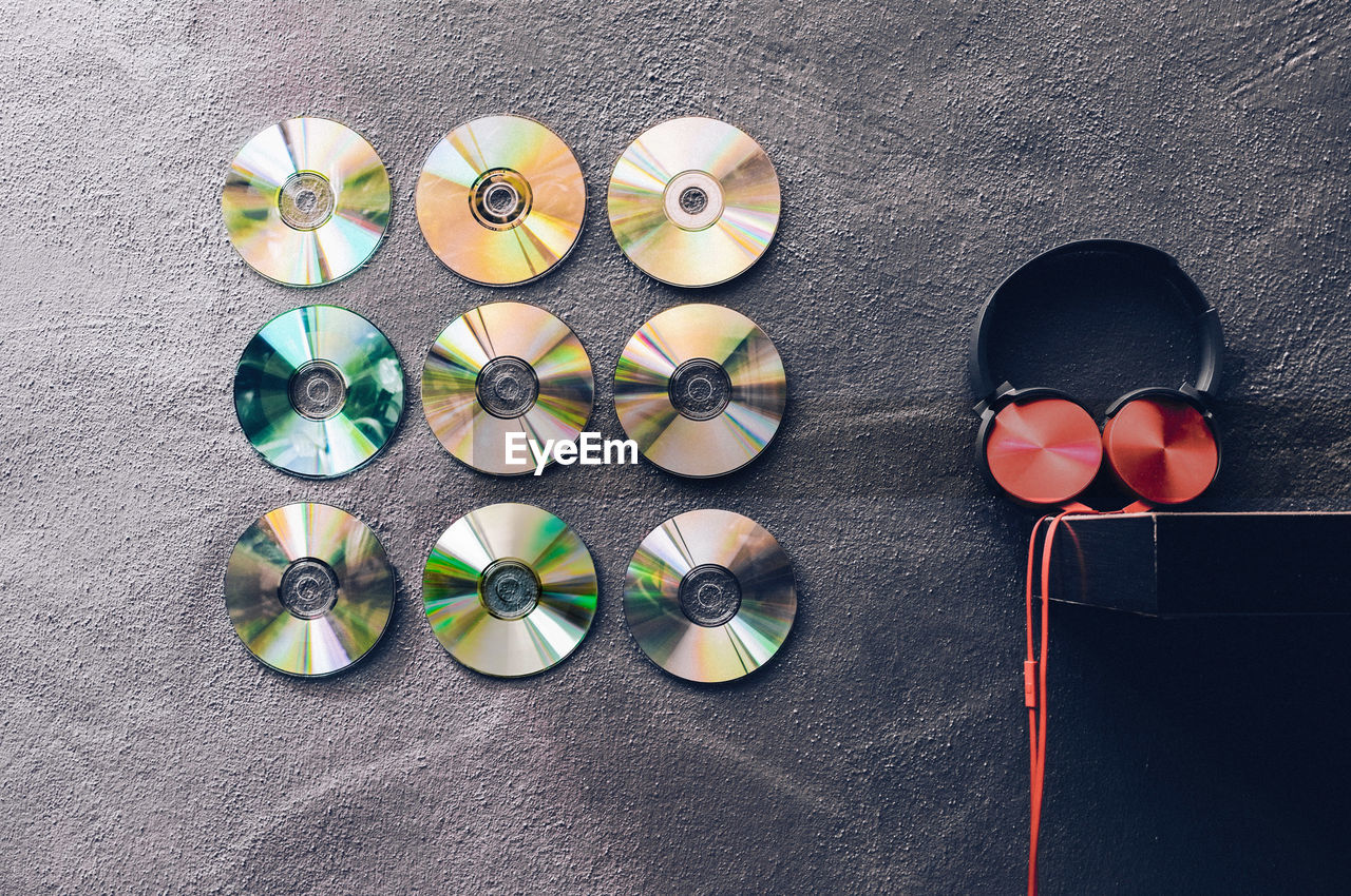 Compact discs decorated over wall by headphones on shelf