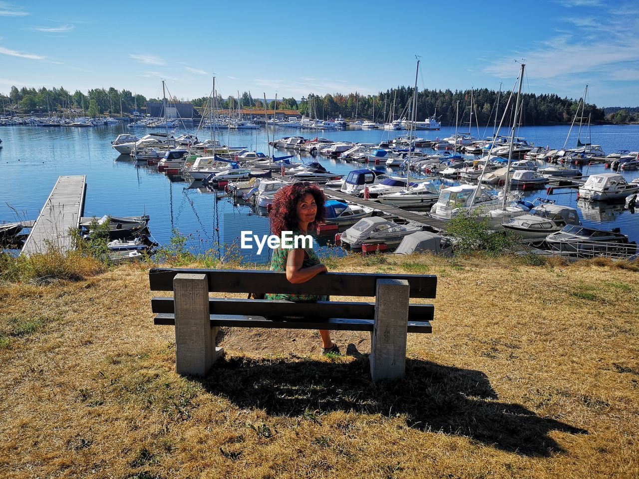 Portrait of woman sitting on bench at harbor