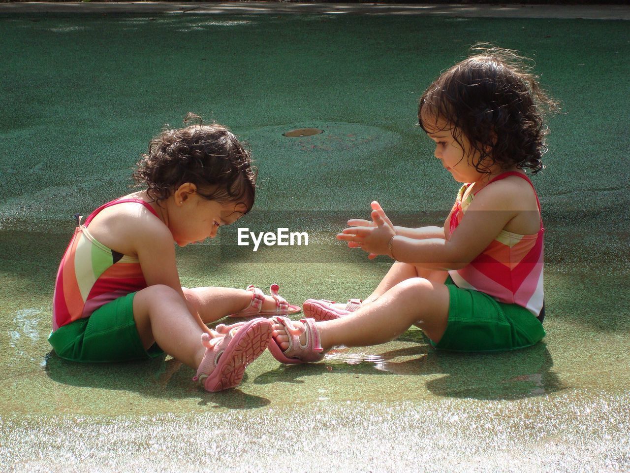 Twin baby girls playing in water on floor