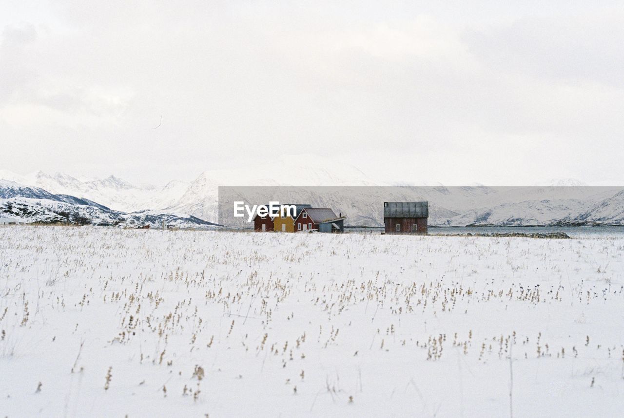 House on snow covered field against sky