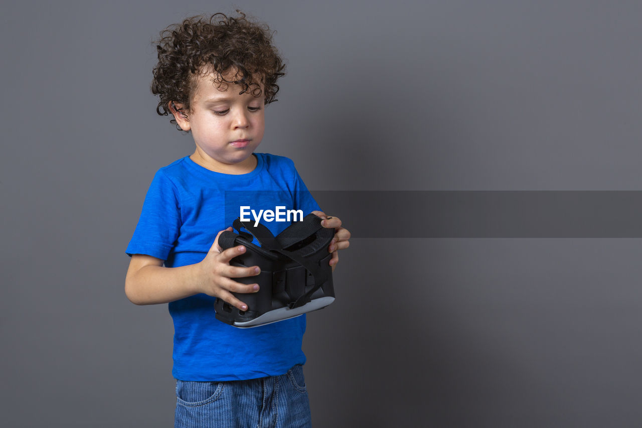 Photo of curly-haired caucasian boy wearing virtual reality glasses