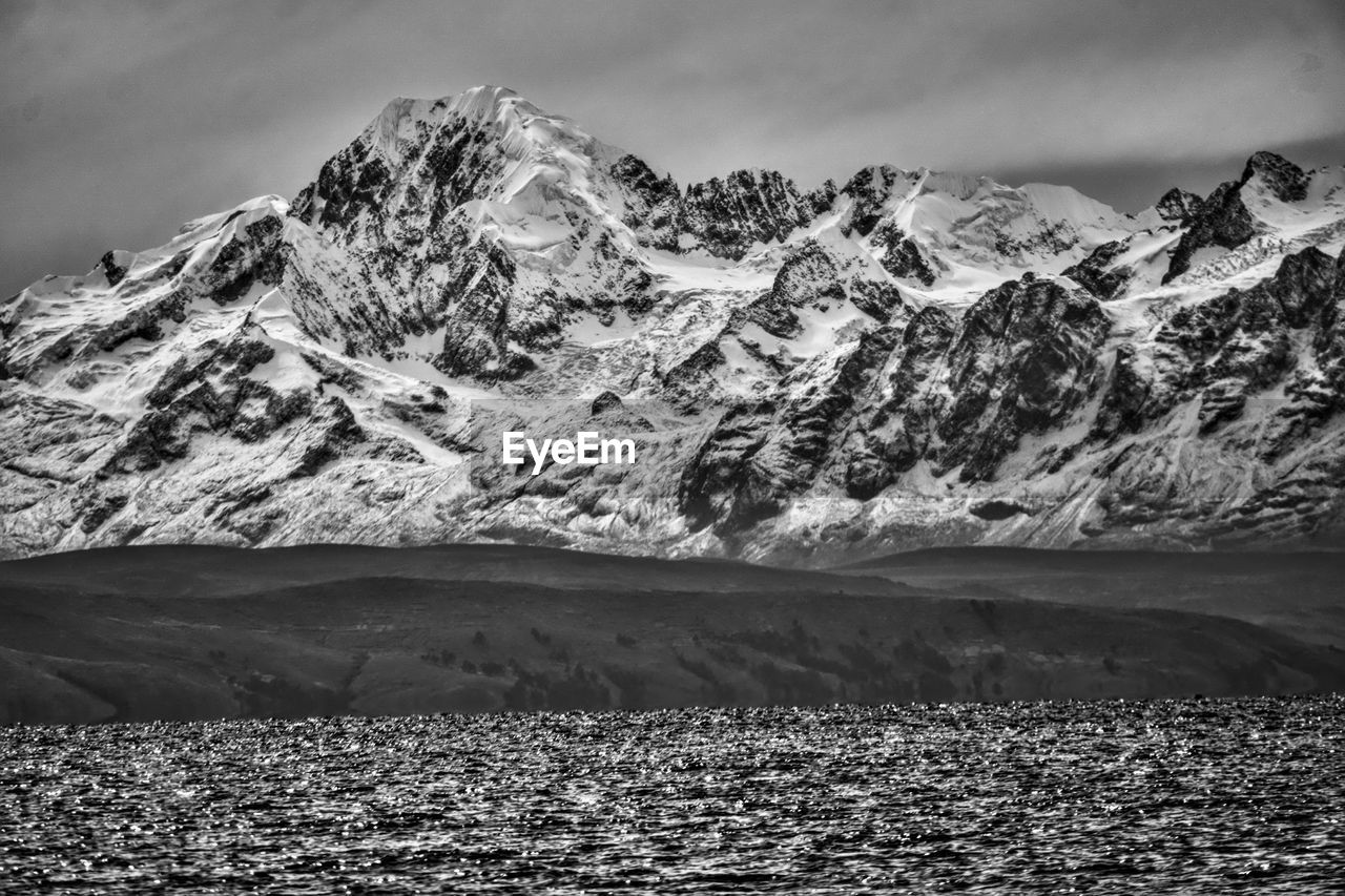 mountain, snow, scenics - nature, cold temperature, environment, black and white, landscape, mountain range, beauty in nature, snowcapped mountain, winter, monochrome, monochrome photography, sky, nature, cloud, water, travel destinations, no people, land, tranquil scene, tranquility, travel, ice, non-urban scene, glacier, extreme terrain, outdoors, day, rock, mountain peak, frozen, tourism, lake