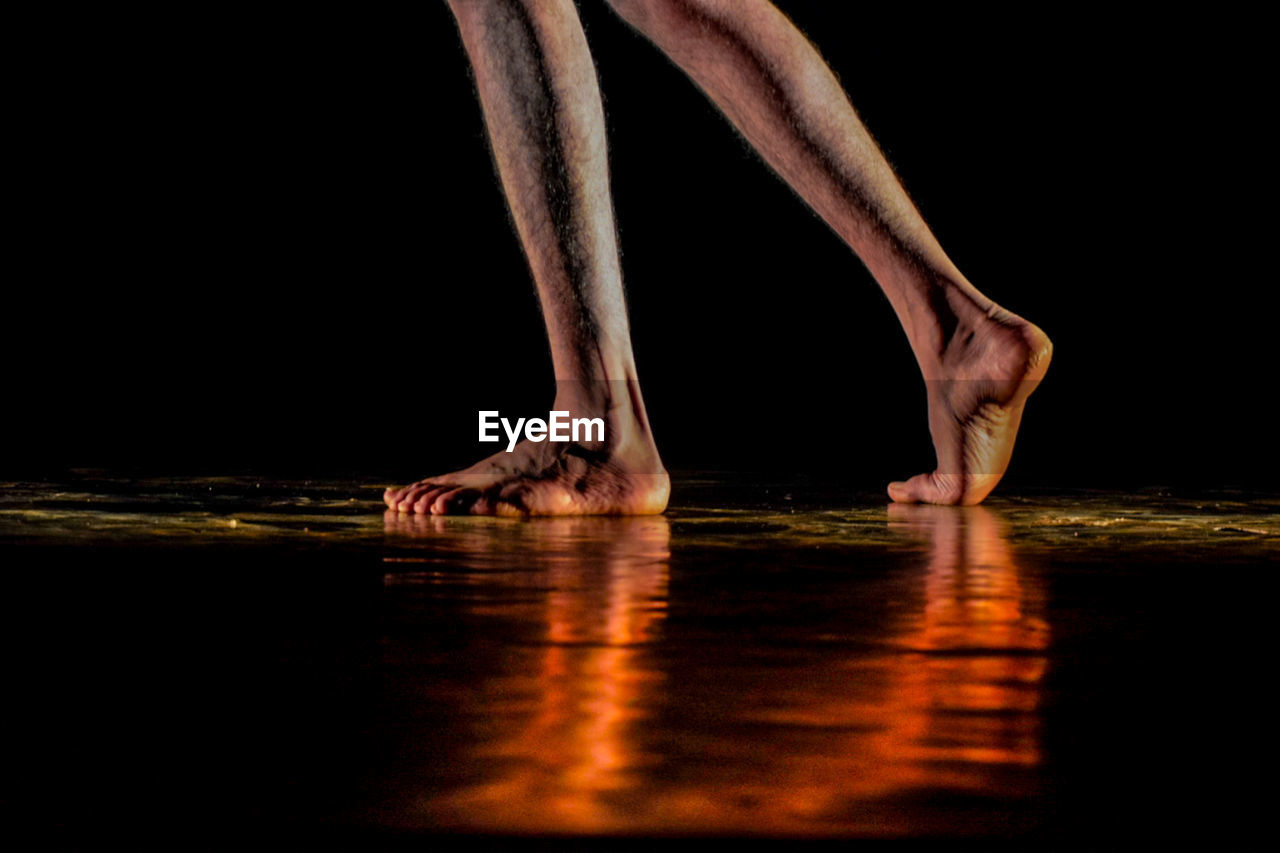 low section of woman walking on sand