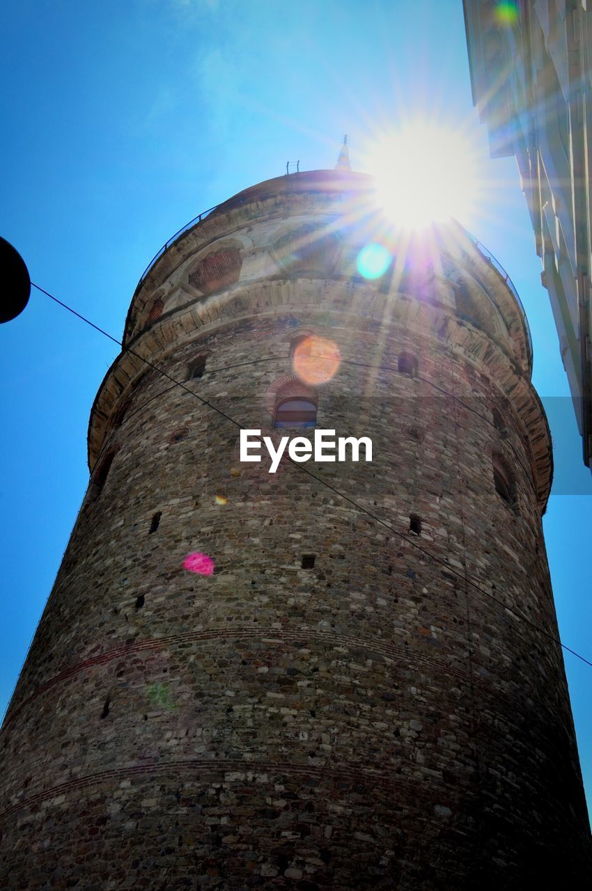 Low angle view of galata tower against sky on sunny day