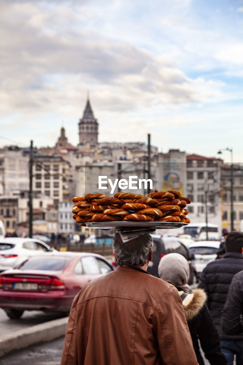 Rear view of man selling food in city against sky