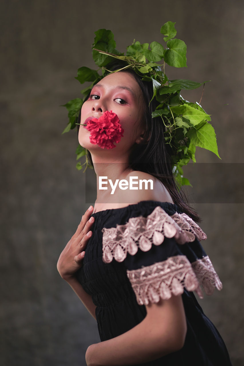 Portrait of young woman standing against plants