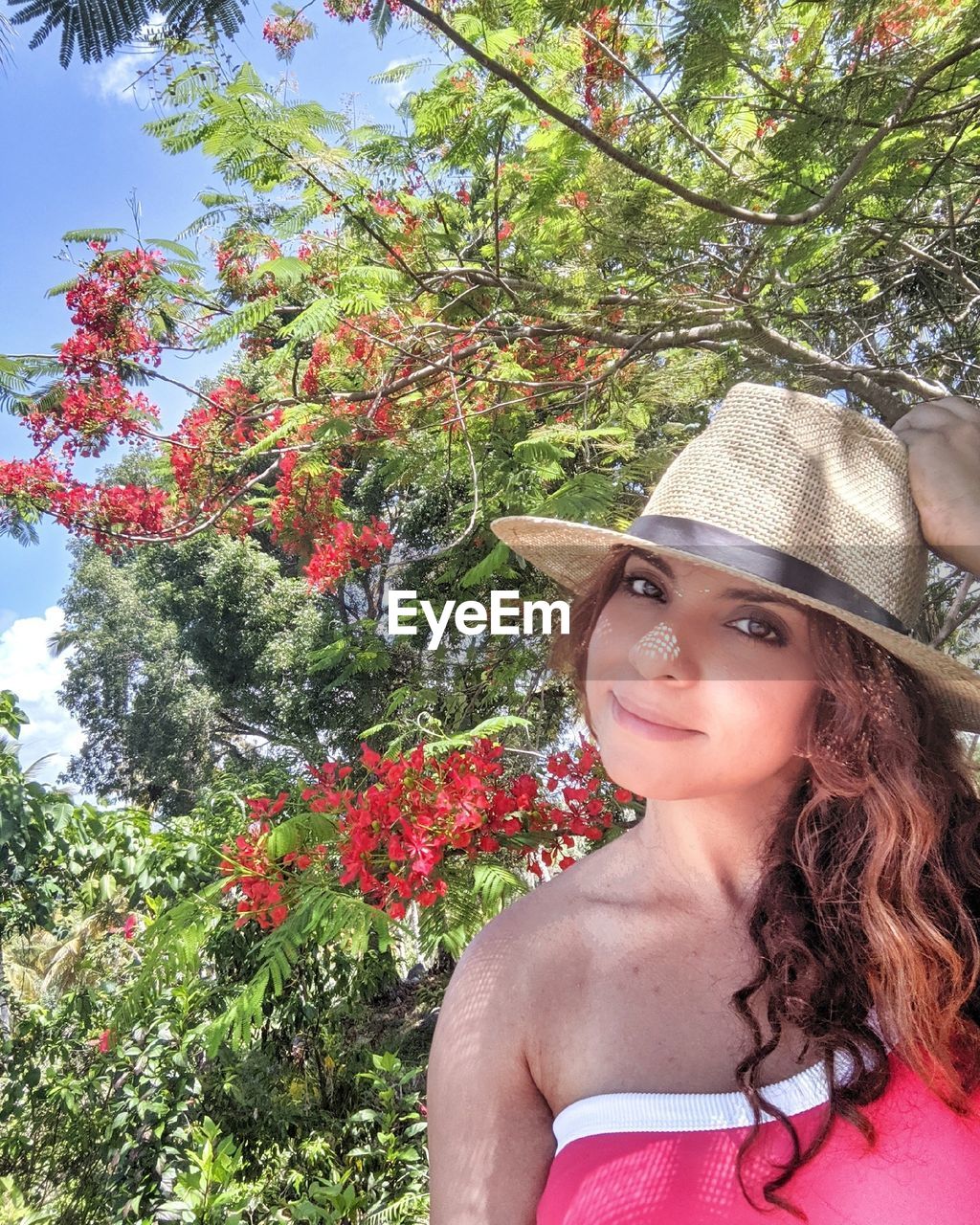 Portrait of woman wearing hat while standing against trees