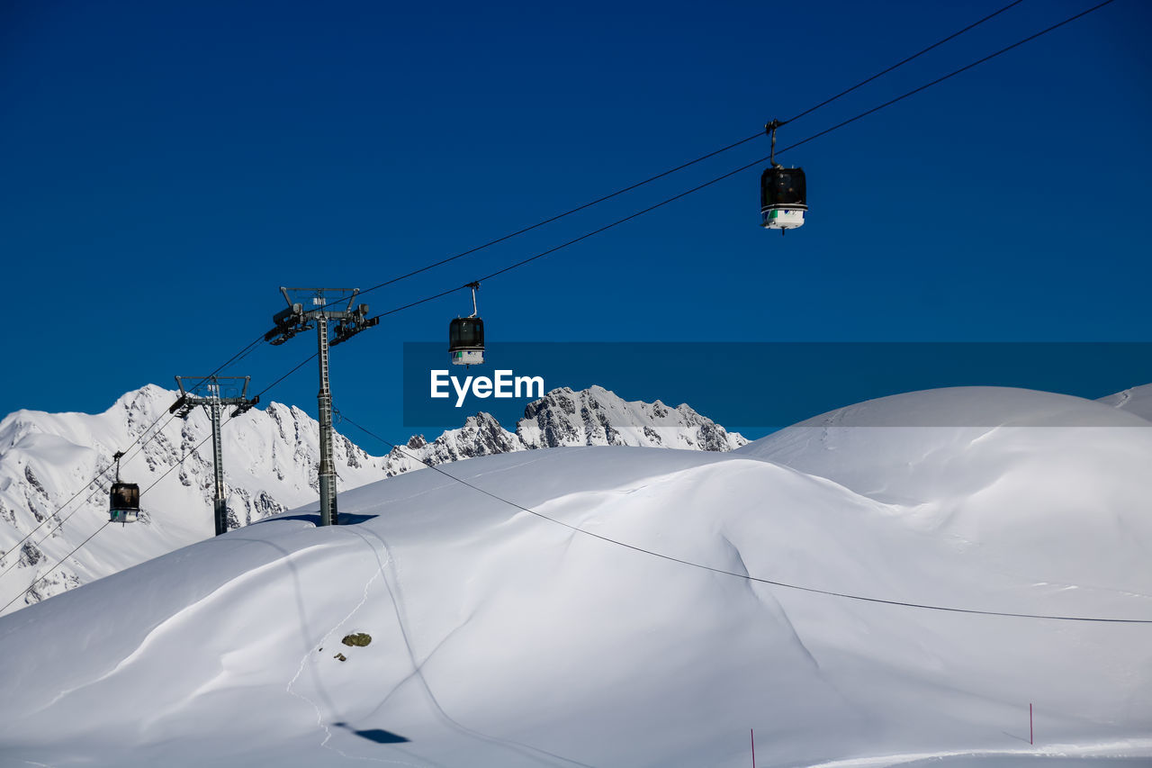 Low angle view of overhead cable car against blue sky