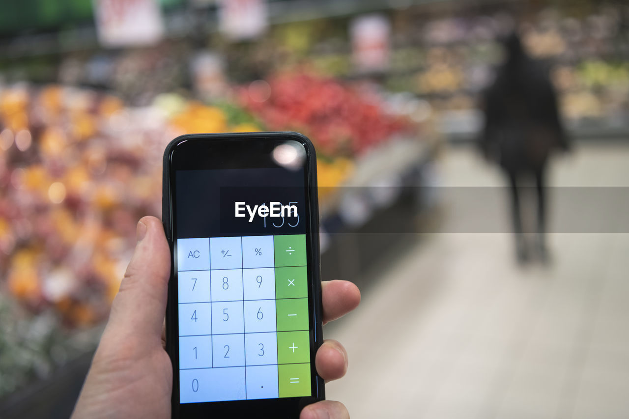 Hand holding calculator in supermarket