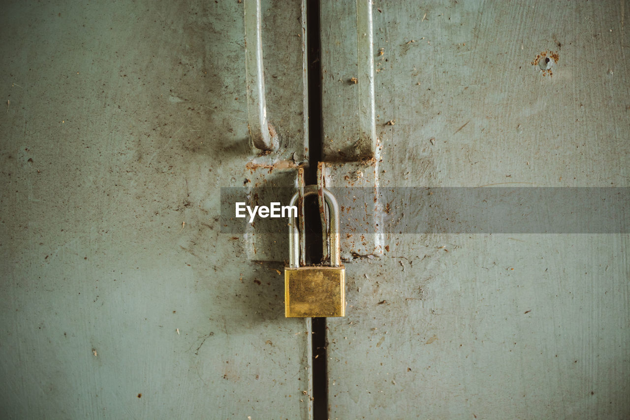 CLOSE-UP OF PADLOCK ON METAL DOOR WITH HANDLE