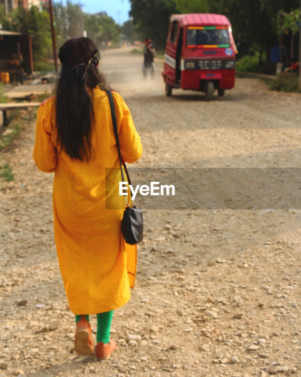 REAR VIEW OF WOMAN WALKING WITH ROAD