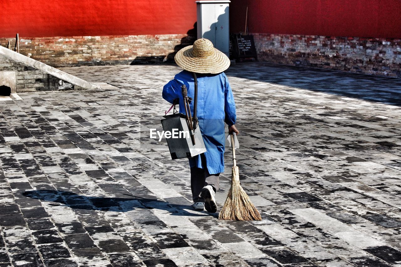 Rear view of a man holding broom