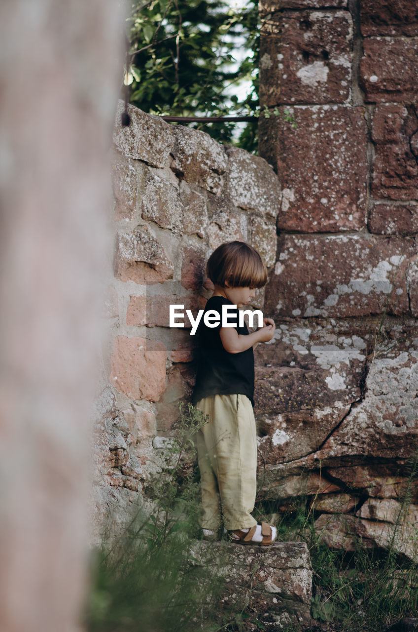 Full length of boy standing against wall