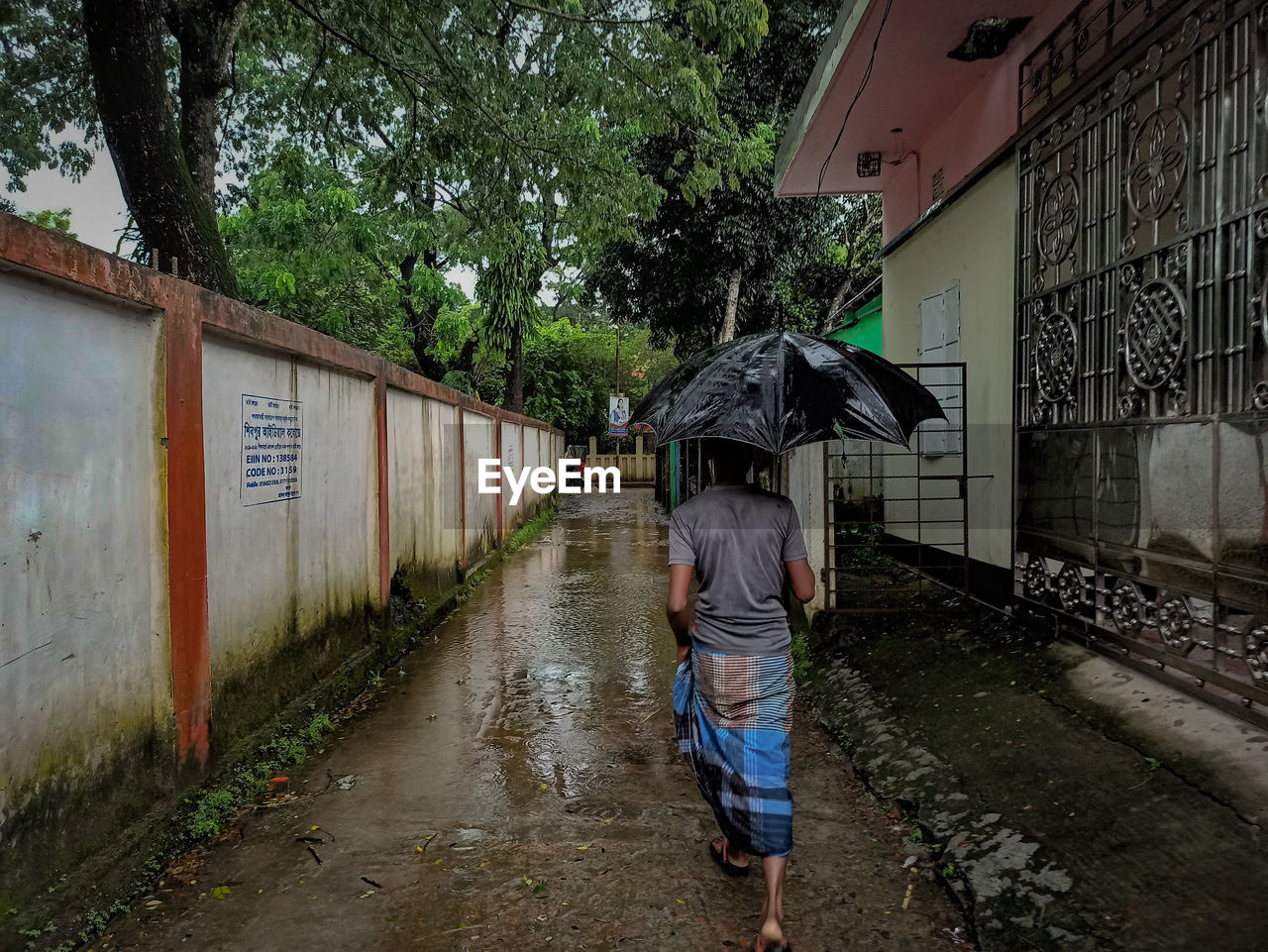Rear view of person on wet road during rainy season