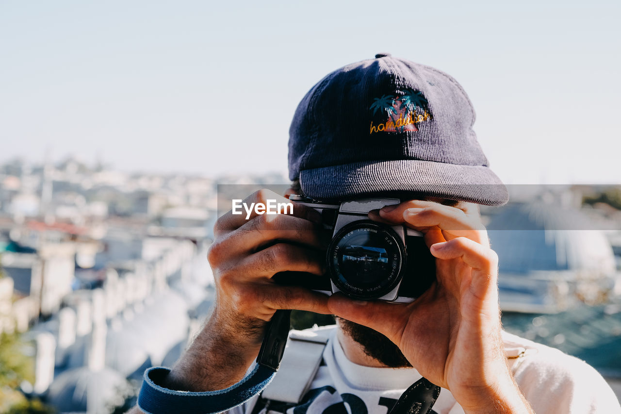 PORTRAIT OF MAN PHOTOGRAPHING CAMERA