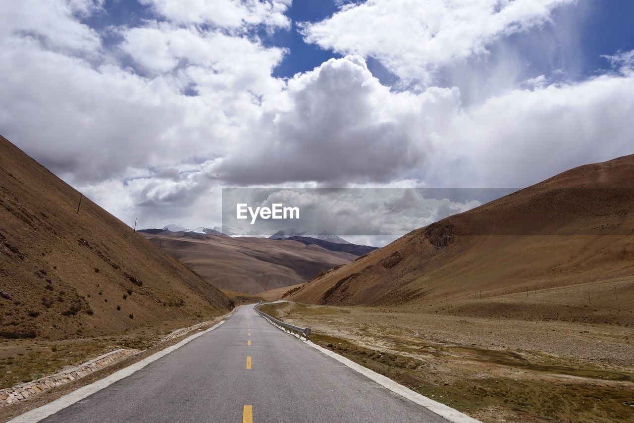 Empty road amidst landscape against sky