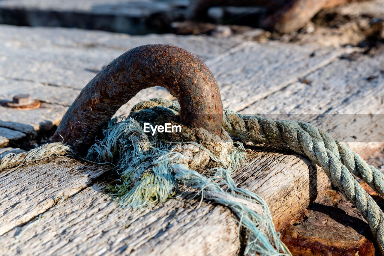 CLOSE-UP OF ROPE ON RUSTY METAL CHAIN