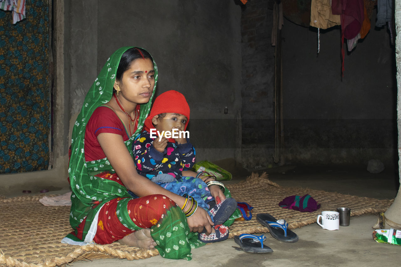 Full length of mother with daughter sitting at home