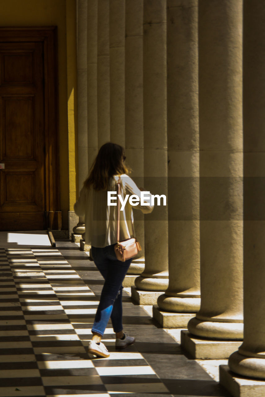 Rear view of woman walking against building