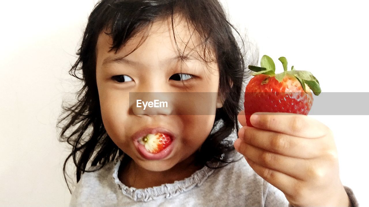 Close-up of girl eating strawberry