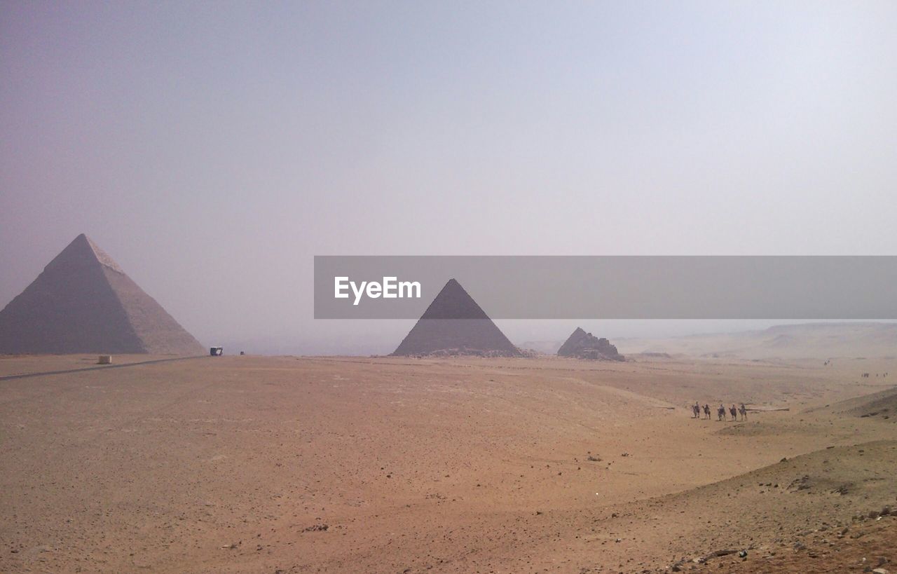 Pyramids in desert against clear sky on sunny day