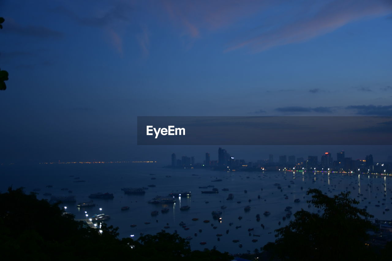 HIGH ANGLE VIEW OF CITY BY SEA AT NIGHT