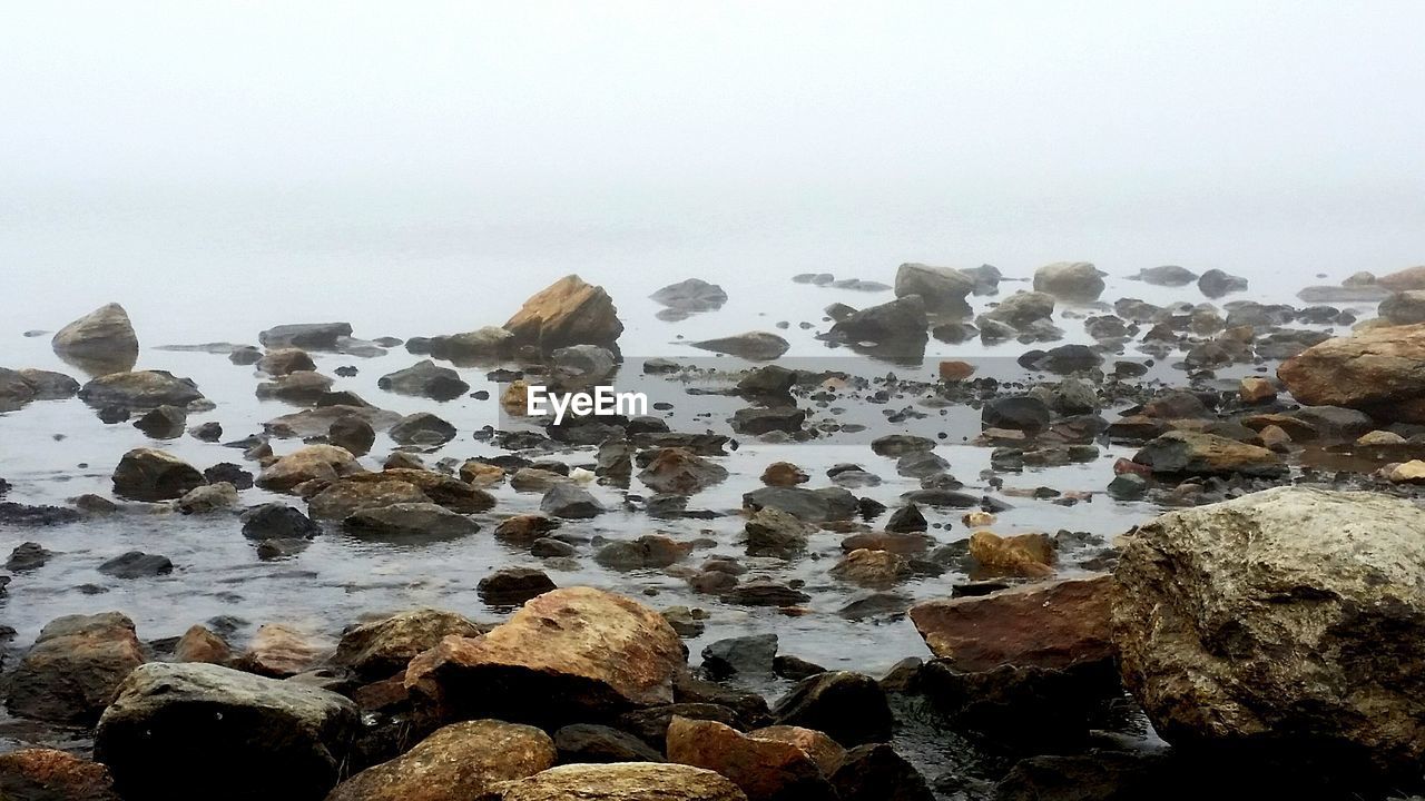 ROCKS ON SHORE AGAINST SKY