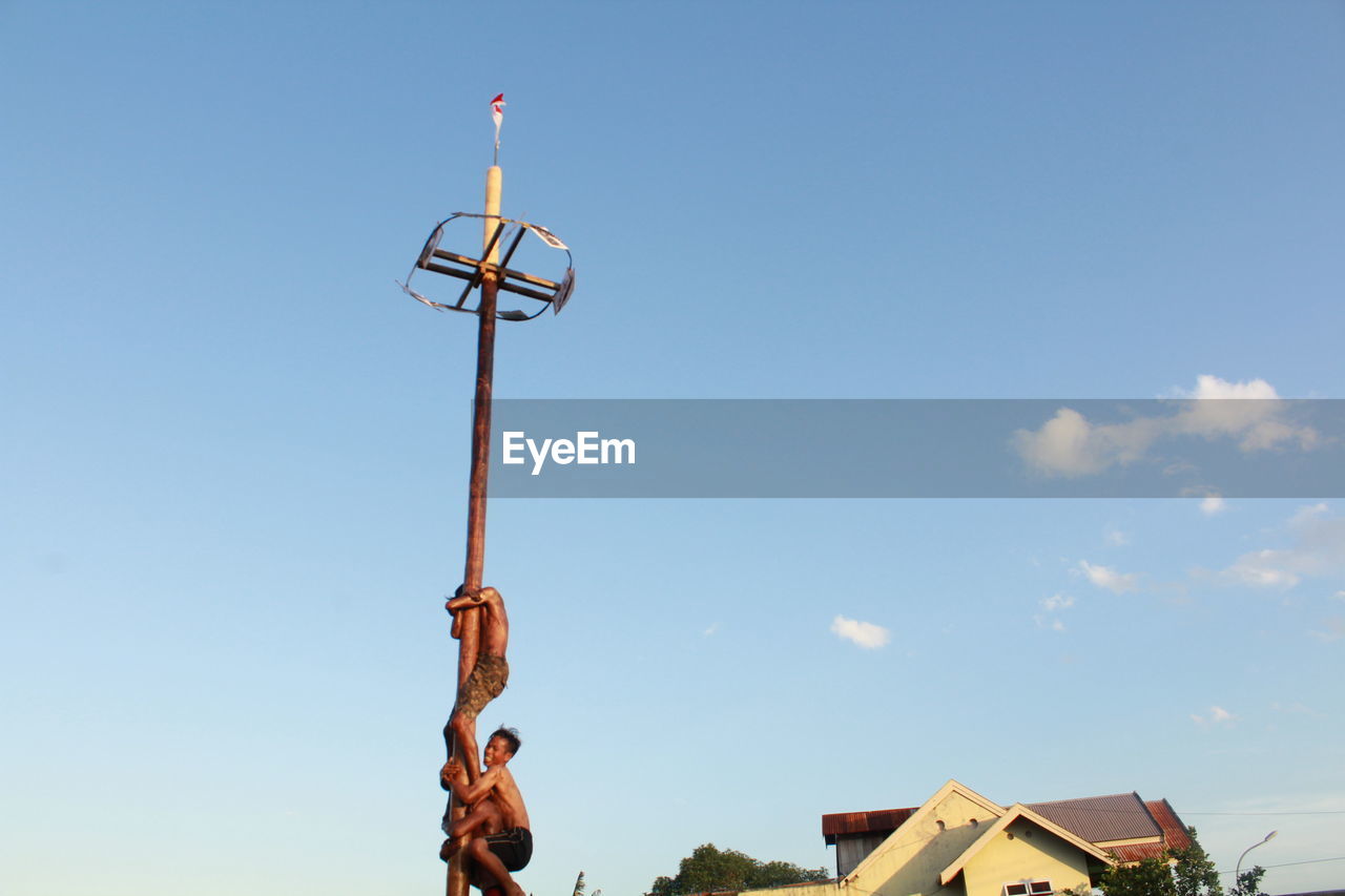 LOW ANGLE VIEW OF MAN HOLDING UMBRELLA AGAINST SKY