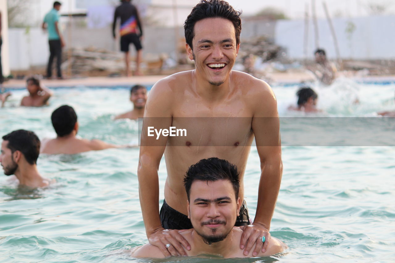 Smiling friends swimming in pool