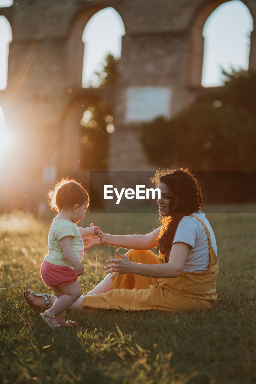 Mother and daughter on field during sunset