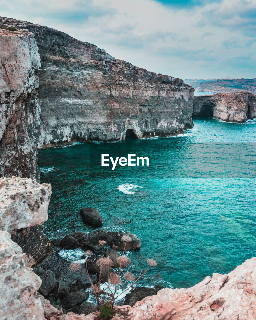 Rock formations on shore against sky