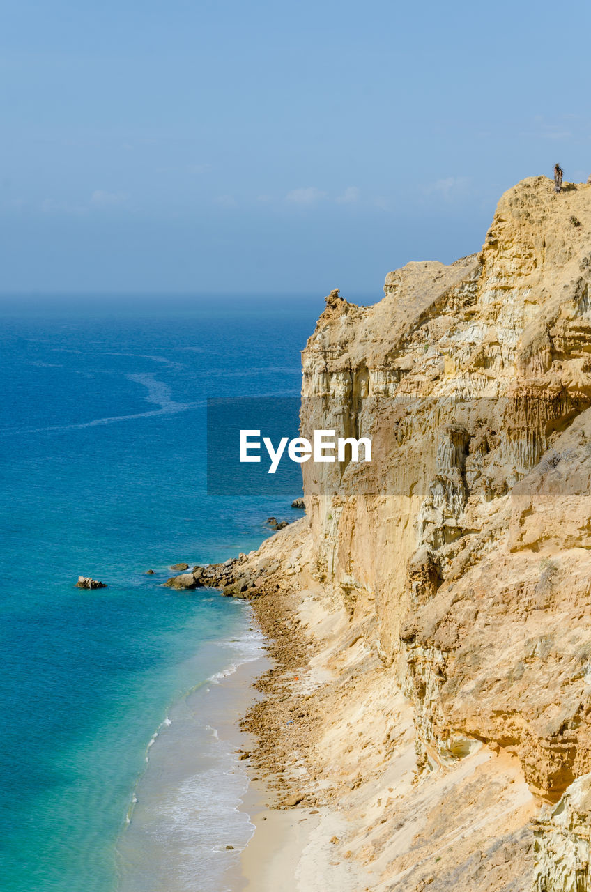 Scenic view of sea by cliff against sky