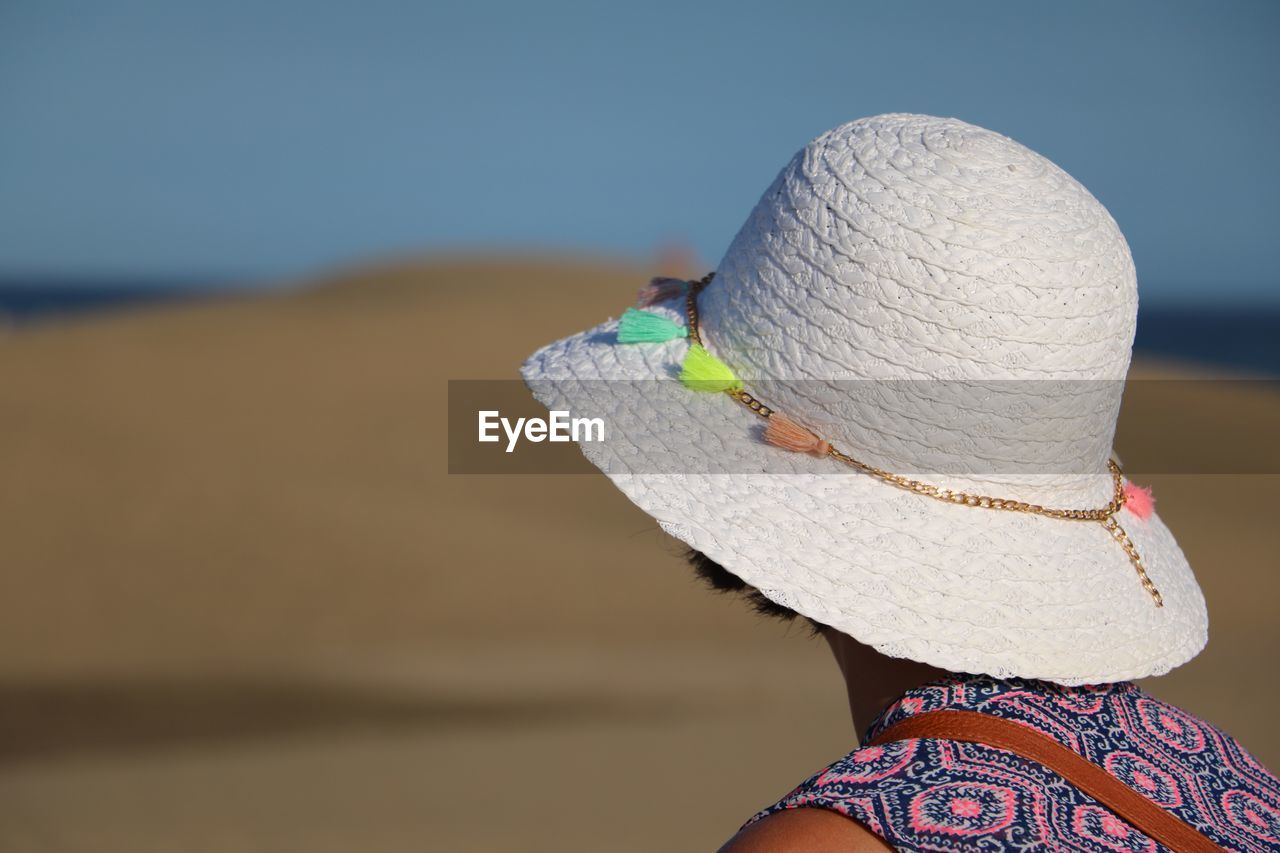 REAR VIEW OF WOMAN WEARING HAT ON BEACH