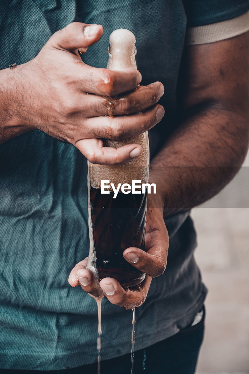 Midsection of man holding drink bottle